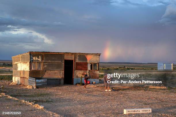 Woman cleans her yeard outside the family home in the newly built section in Snake Park, an informal settlement, on January 28 outside Hope Town,...