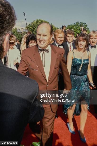 American actor Robert Duvall, wearing a brown suit over a white shirt with a bow tie, and American dancer Sharon Brophy, who wears a blue dress,...