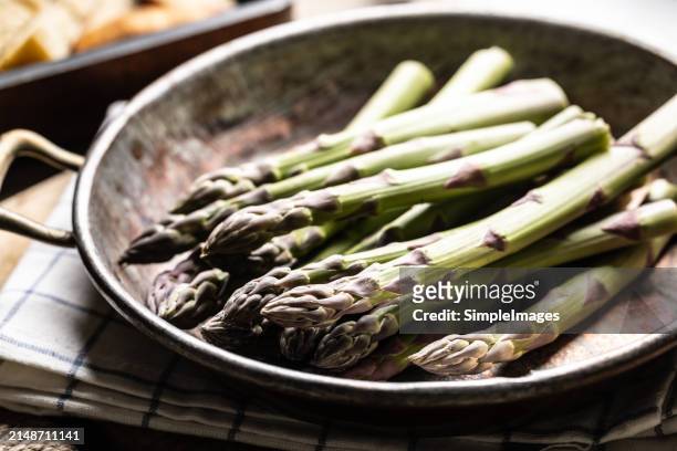 fresh organic asparagus in an old metal pan on rustic wooden table. - slovakia country stock pictures, royalty-free photos & images