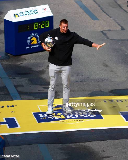 Boston Marathon Grand Marshal and former New England Patriot Rob Gronkowski shows off the winner's trophy at the finish line during the 128th Boston...