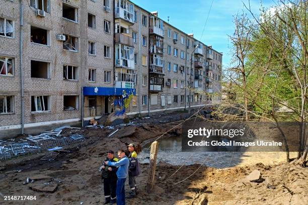 Municipal service workers eliminate consequences of a missile strike on a five-story residential building on April 15, 2024 in Sloviansk, Donetsk...