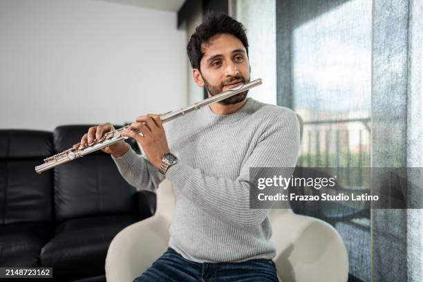 mid adult man playing the flute at home - flauta imagens e fotografias de stock