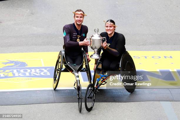 Marcel Hug of Switzerland , and Eden Rainbow Cooper of Great Britain pose with the trophy on the finish line after winning the professional Women's...