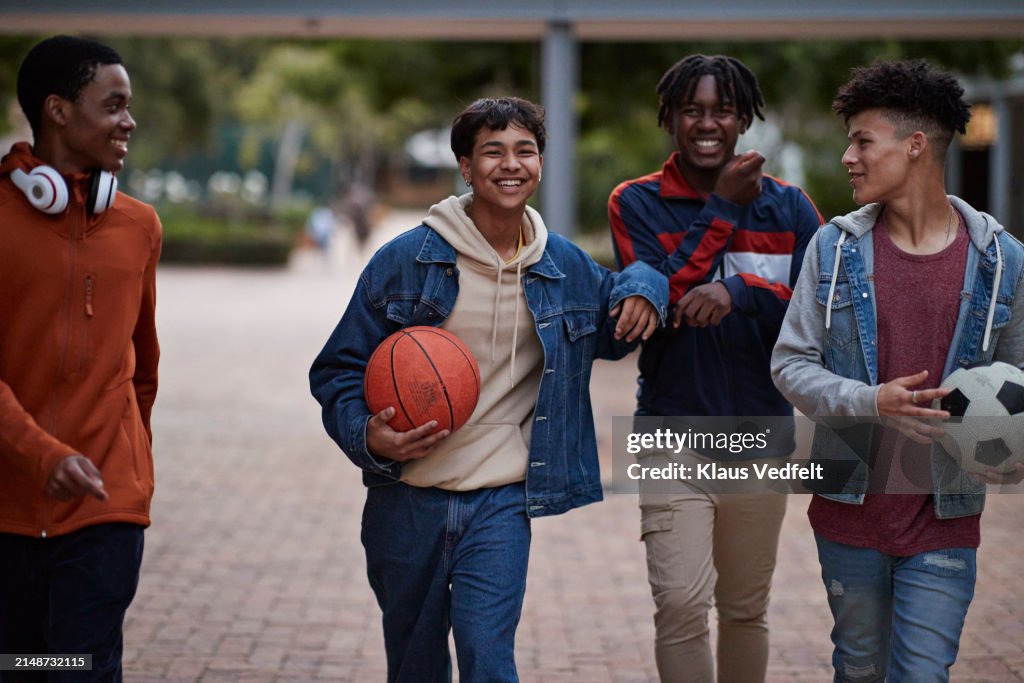 Happy male friends talking while walking with balls