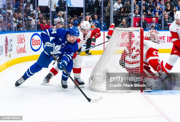 Auston Matthews of the Toronto Maple Leafs shoots against Dylan Larkin and James Reimer of the Detroit Red Wings during the third period at...