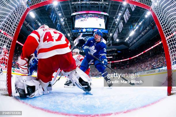 Auston Matthews of the Toronto Maple Leafs stands in front of the net against James Reimer of the Detroit Red Wings during the third period at...