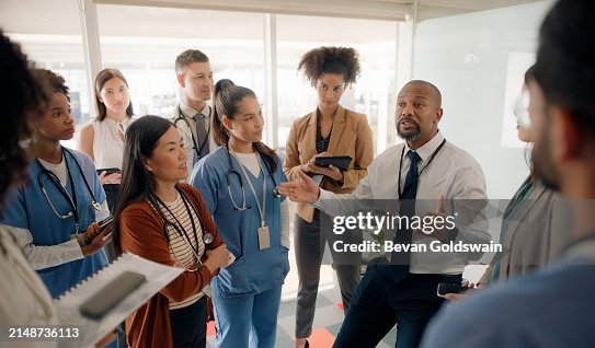Boardroom, discussion and executive talking to staff in hospital for healthcare of patients. Man, training and mentor of employees or nurses and tablets for notes of speech by leader in medical field Boardroom, discussion and executive talking to staff in hospital for healthcare of patients. Man, training and mentor of employees or nurses and tablets for notes of speech by leader in medical field