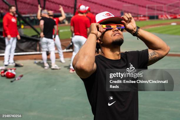 Santiago Espinal of the Cincinnati Reds watches the Solar Eclipse before a game against the Milwaukee Brewers at Great American Ball Park on April...