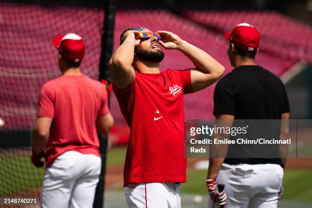 Nick Martini of the Cincinnati Reds watches the Solar Eclipse before a game against the Milwaukee Brewers at Great American Ball Park on April 08,...