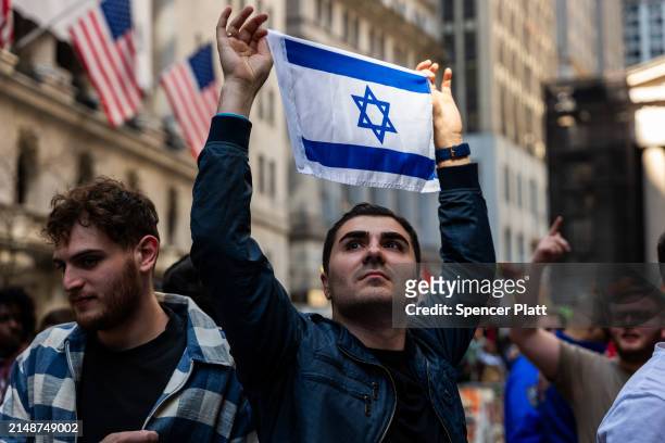 Man holds up an Israeli flag as pro Palestinian protesters confront a small group of Israeli demonstrators during dueling events outside of the New...