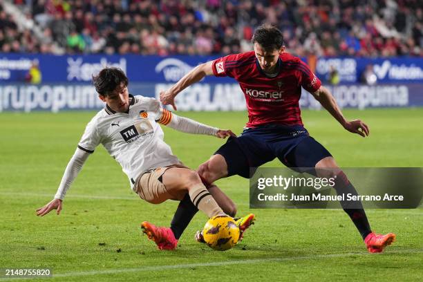 Hugo Guillamon of Valencia CF tackles Ante Budimir of CA Osasuna during the LaLiga EA Sports match between CA Osasuna and Valencia CF at Estadio El...