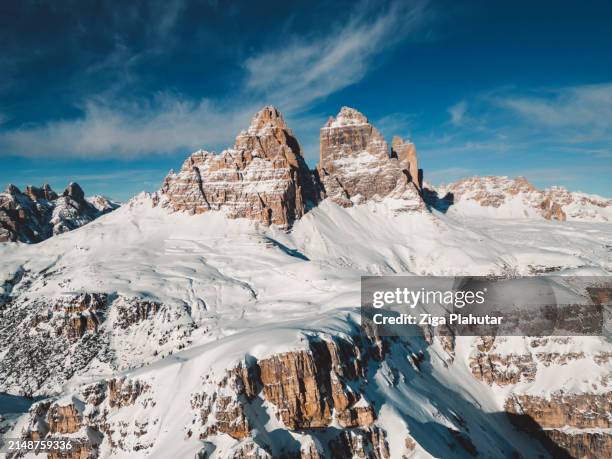 rocky mountain peak rising above the blanket of snow covering the rest of the mountain - ziga plahutar stock pictures, royalty-free photos & images