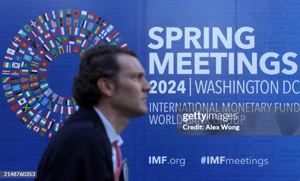 Man passes by a sign during the annual Spring Meetings outside the IMF headquarters on April 15, 2024 in Washington, DC. The World Bank and IMF...