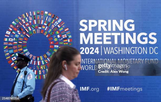 Woman passes by a sign during the annual Spring Meetings outside the IMF headquarters on April 15, 2024 in Washington, DC. The World Bank and IMF...
