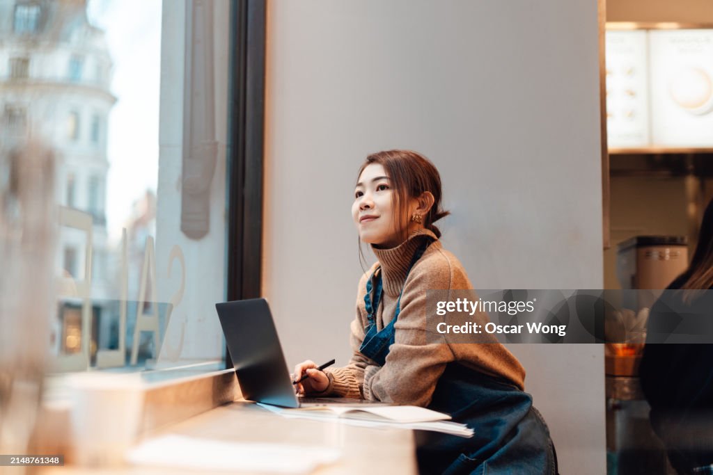 Female business owner doing accounting and bookkeeping with laptop, sitting in cafe