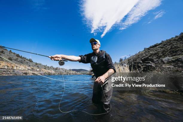 active man catches fishes while standing in the river - fishing line stock pictures, royalty-free photos & images