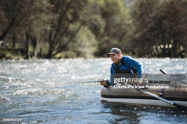 l'uomo di mezza età pesca a mosca da un gommone - pescatore foto e immagini stock