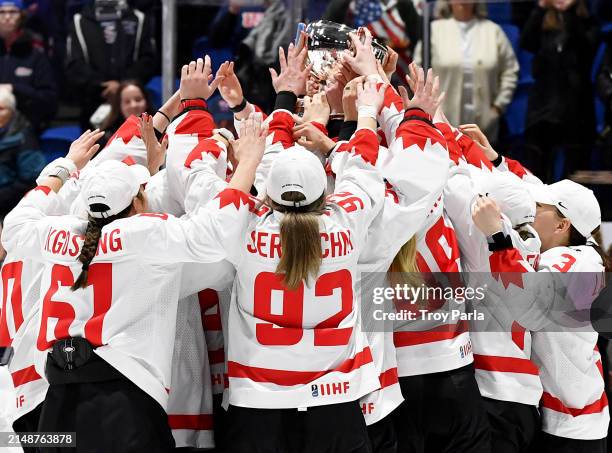 Members of Team Canada reach to touch the Championship Trophy after winning in OT against United States during the 2024 IIHF Women's World...