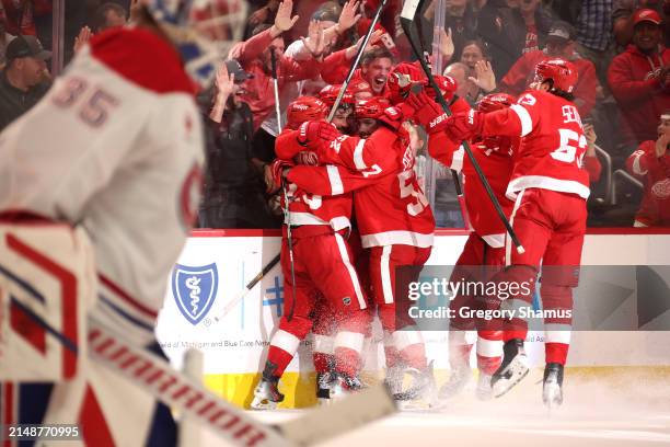 Lucas Raymond of the Detroit Red Wings celebrates his game winning overtime goal for a 5-3 win with teammates behind Sam Montembeault of the Montreal...