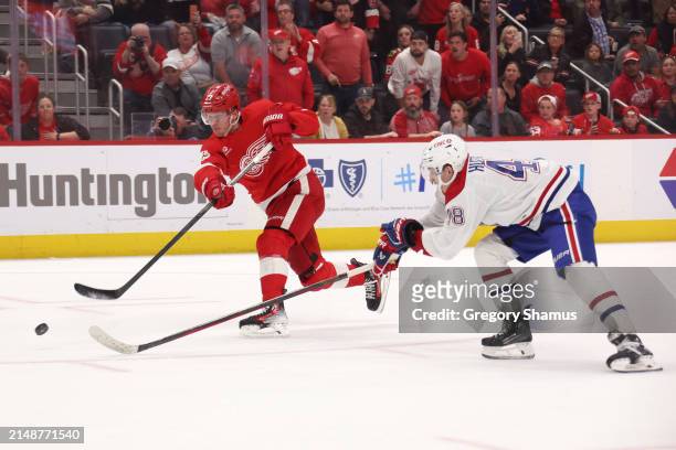 Lucas Raymond of the Detroit Red Wings scores the game winning goal past the stick of Lane Hutson of the Montreal Canadiens at Little Caesars Arena...