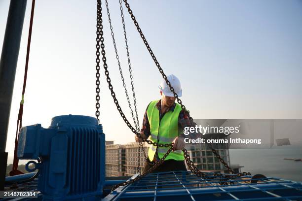 ein ingenieur arbeitet mit einem hebezeug, um wartungsarbeiten an der hlk-anlage und der kältemaschine auf dem dach eines gebäudes durchzuführen. - hochziehen stock-fotos und bilder