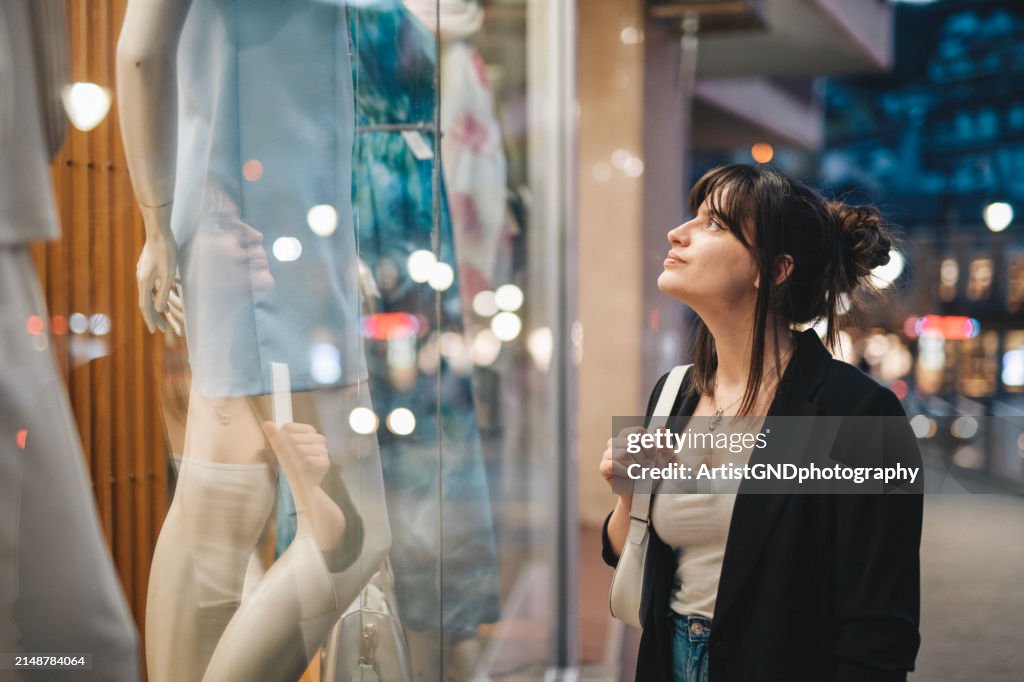 Woman window shopping on city street.