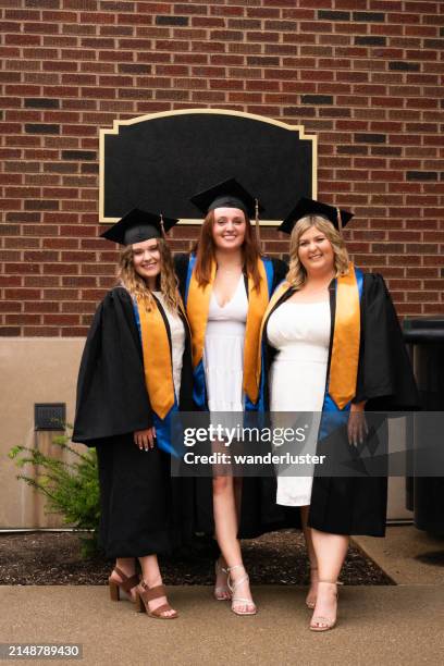 three smiling female college graduates in cap and gowns - gold shoe stock pictures, royalty-free photos & images