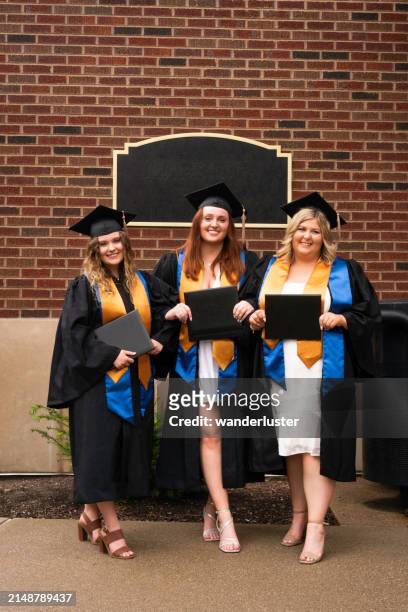 three smiling female college graduates hold diplomas - gold shoe stock pictures, royalty-free photos & images