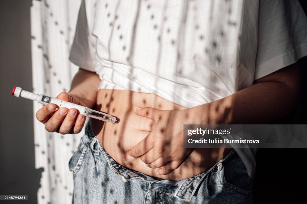 Injections for weight loss with Semaglutide. An obese woman gives a hormonal injection into the abdomen with a pen syringe.