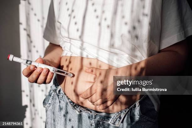 injections for weight loss with semaglutide. an obese woman gives a hormonal injection into the abdomen with a pen syringe. - semaglutide - fotografias e filmes do acervo