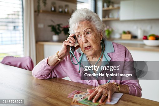 Telephone scams targeting seniors. Scammer making phone call with elderly woman, asking for money, demanding personal, sensitive informations over phone without verification. Telephone scams targeting seniors. Scammer making phone call with elderly woman, asking for money, demanding personal, sensitive informations over phone without verification.