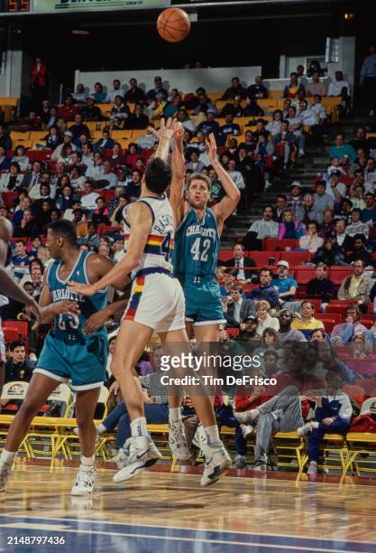 Mike Gminski, Center for the Charlotte Hornets attempts a three point jump shot as Blair Rasmussen, Center for the Denver Nuggets jumps to block...
