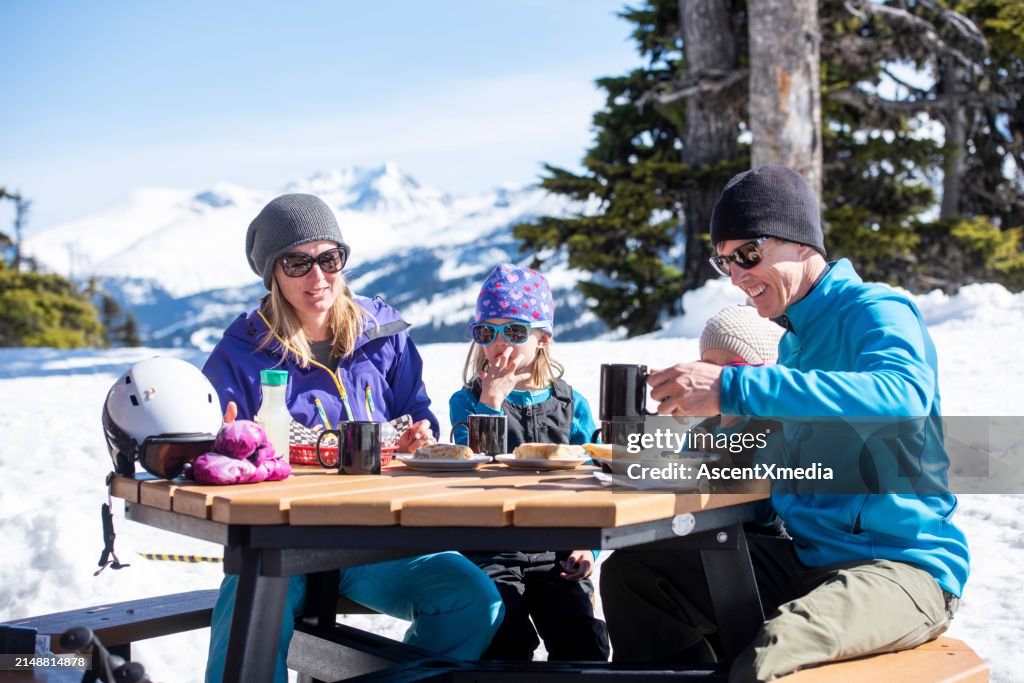 Ski family enjoy snack outdoors