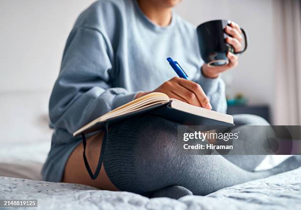 woman, coffee and notebook in bedroom with planning, morning peace and daily self care at home. female person, mug and writing in journal with pen for feelings, ideas and information at apartment - dagbok bildbanksfoton och bilder