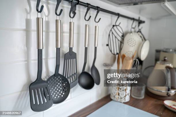 kitchen utensils hanging on hooks on rod above stove - ustensile de cuisine photos et images de collection
