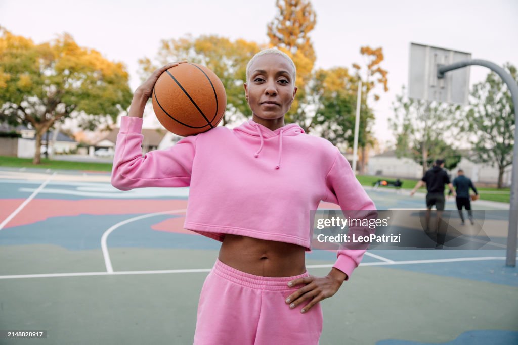 Basketball player portrait in a outdoor court wearing a pink hooded shirt