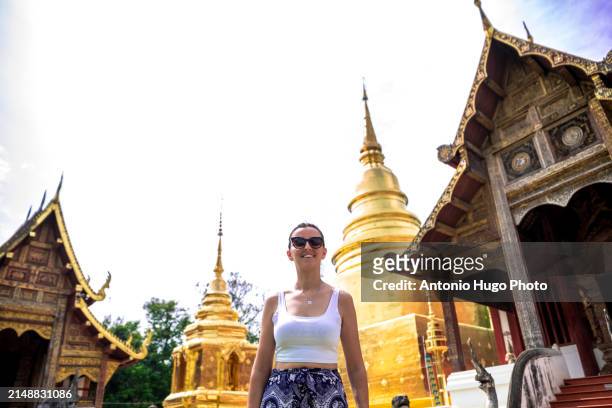 portrait of a young woman walking in the temple of wat phra singh in chang mai. - singh stock pictures, royalty-free photos & images