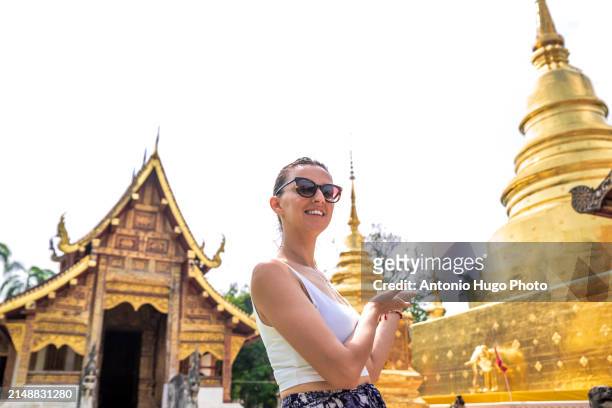 young woman visiting the temple of wat phra singh in chang mai - singh stock pictures, royalty-free photos & images