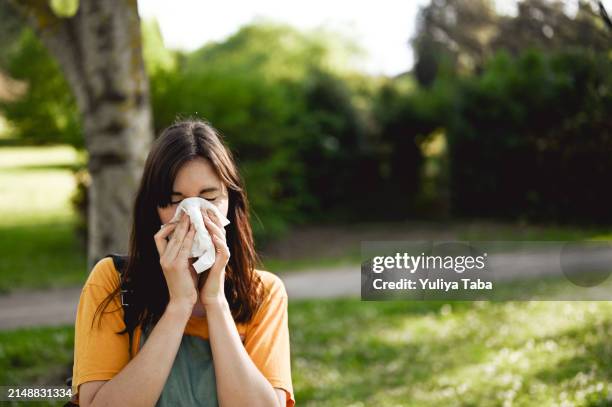 woman sneezing in park - allergiemedicijn stockfoto's en -beelden