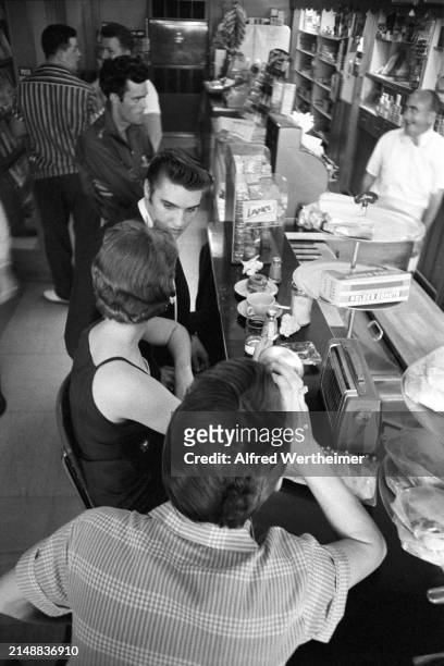 Alfred Wertheimer/MUUS Collection via Getty Images) American musician Elvis Presley as he shares a meal with his date, Bobbi Owens , at the counter...