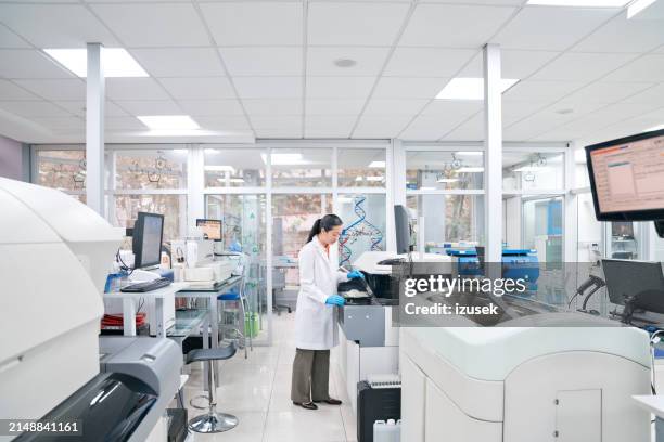 female medical worker wearing lab coat while working in laboratory - wide angle stock pictures, royalty-free photos & images
