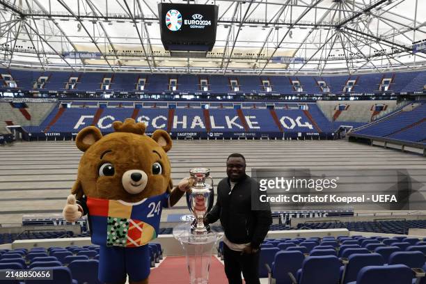 Gerald Asamoah, ambassador of Gelsenkirchen poses with the official EURO 2024 trophy and Albärt, offical UEFA EURO 2024 mascot at the Arena during...
