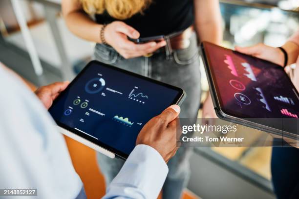 team analyzing data on portable devices - business strategy stock pictures, royalty-free photos & images