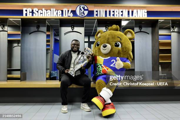 Gerald Asamoah, ambassador of Gelsenkirchen poses with Albärt, offical UEFA EURO 2024 mascot and the UEFA EURO 2024 Trophy in the players cabin of...