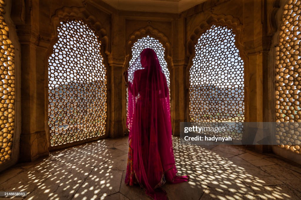Young Indian woman looking through the window