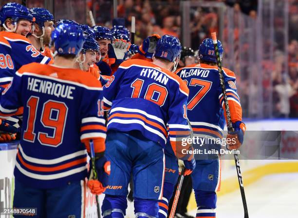 Connor McDavid of the Edmonton Oilers is congratulated by his teammates at the bench on recording his 100th assist of the season during the second...