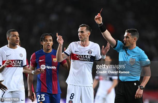 Referee Istvan Kovacs shows a red card to Ronald Araujo of FC Barcelona following a foul on Bradley Barcola of Paris Saint-Germain during the UEFA...