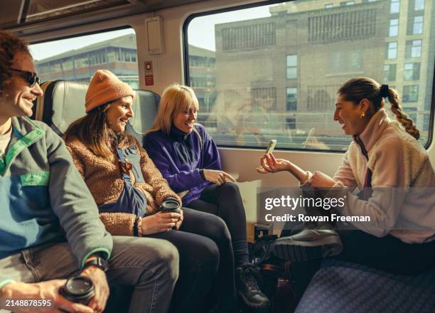 young friends commuting laughing at something on the phone - transportation stock pictures, royalty-free photos & images