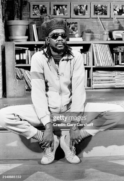 View of Jamaican Reggae musician Peter Tosh seated on a low stage during an interview at MTV Studios, New York, New York, May 19, 1983.