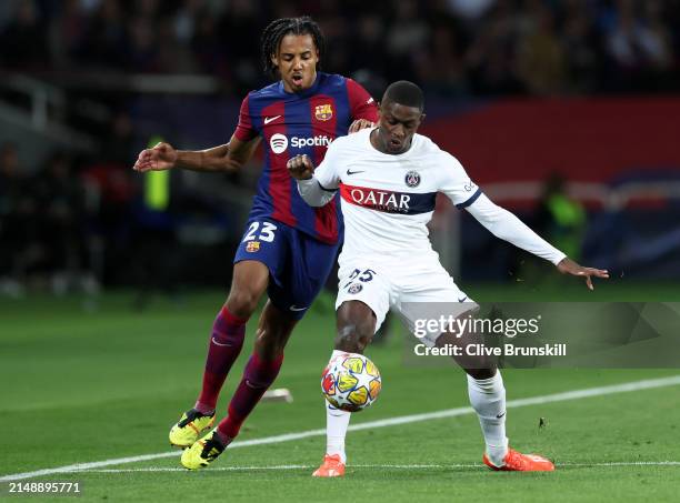 Nuno Mendes of Paris Saint-Germain holds off a challenge from Jules Kounde of FC Barcelona during the UEFA Champions League quarter-final second leg...